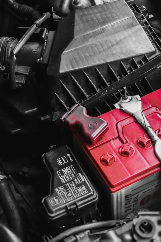 A car battery and its terminals in an engine bay