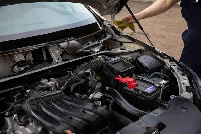 A mechanic checking the battery in an open engine bay
